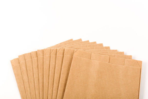 Nouveaux sacs en papier artisanal brun en forme de éventail sur un fond blanc. Emballage de marchandises, nourriture, lettres. Gros plan
. - Photo, image