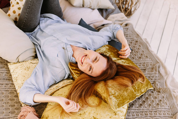 Ihana nuori nainen makaa kotona valoisassa sängyssä ja hymyilee. Kuva kirkas, aurinkoinen, keltainen väri
. - Valokuva, kuva