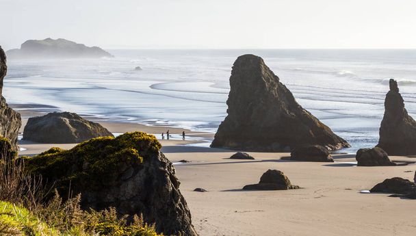 Tarde tranquila em Bandon Oregon com marés baixas revelando uma praia de areia com grandes rochas adicionando drama à paisagem no sul da Costa do Oregon
 - Foto, Imagem