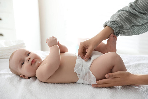 Mother changing her baby's diaper on table - Photo, image