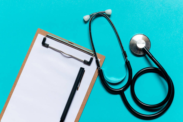 Stethoscope and notepad on blue background. Heart check or health check concept. - Photo, image
