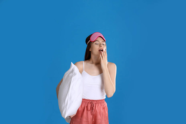 Young woman with pillow and sleep mask on blue background - Photo, image