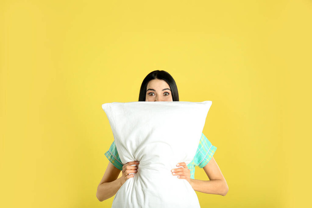 Young woman with pillow on yellow background - Φωτογραφία, εικόνα