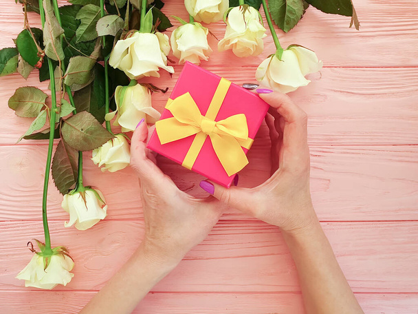 mains féminines tenir boîte cadeau, fleur rose sur fond en bois
 - Photo, image