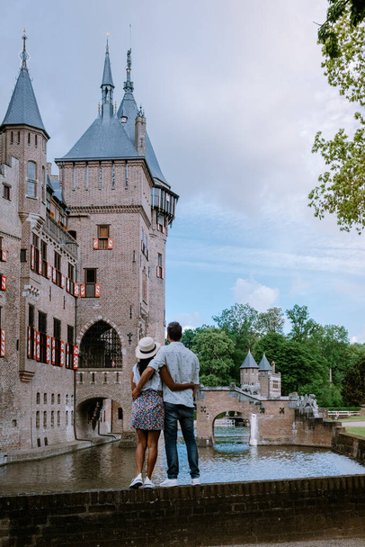 couple men and woman visit a castle in the Netherlands, Castle de Haar Netherlands Utrecht on a bright, young couple men and woman mid age walking in the castle garden - Photo, Image