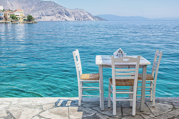 Bílé židle se stoly v typické řecké taverně u moře ve městě Symi - Fotografie, Obrázek