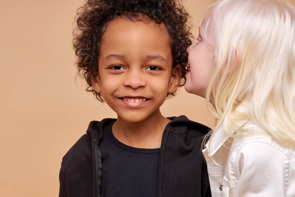 albino girl tells a secret in the ear of african boy - Photo, image