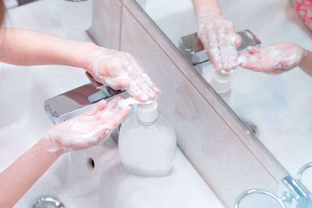 Concepto de higiene. Lavarse las manos con jabón debajo del grifo con agua. - Foto, imagen