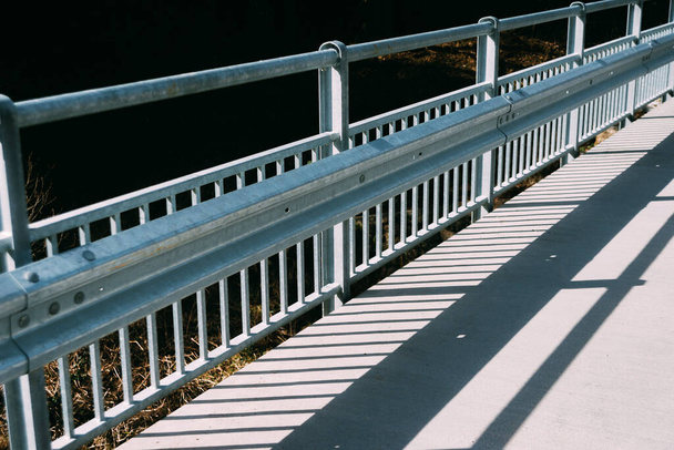 αφηρημένο μοτίβο των σκιών της γέφυρας κιγκλίδωμα στο πεζοδρόμιο στη γέφυρα - Φωτογραφία, εικόνα