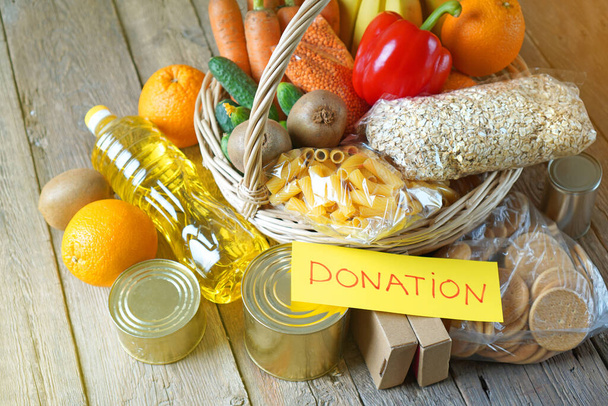 Концепция пожертвования продуктов питания с различными продуктами в корзине с текстом Пожертвование
 - Фото, изображение