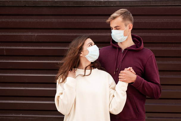 Νεαρό ζευγάρι με μάσκες προσώπου σε καιρό πανδημίας ιών στην πόλη - Φωτογραφία, εικόνα
