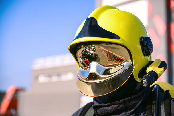 白昼のレーストラックに黄色のヘルメットと反射性の監視を持つ消防士 - 写真・画像