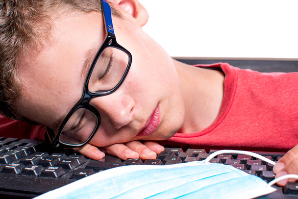 Kind schläft mit Mundschutz über Tastatur ein - Foto, Bild