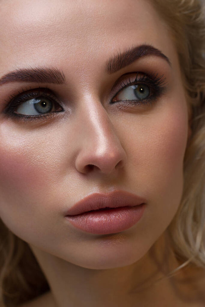 Close-up of woman's lips with fashion natural beige lipstick makeup. Macro sexy pale lipgloss make-up . Gentle pure skin and wavy blonde hair. Cosmetology, Spa, increase in lips - Фото, изображение