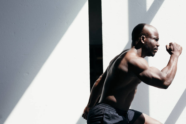 Muscular african american man running on white background - Foto, Bild