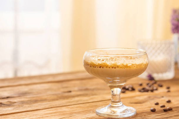 ダルゴナコーヒーはふわふわのホイップコーヒーラテフォーム。砂糖瓶、コーヒー、花のレシピを作ります。シャンパンソーサーガラスとミルクで準備された飲み物 - 写真・画像