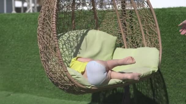 Спящий мальчик, качающийся на трости, проскакивает мимо своей мамы в сло-мо - Кадры, видео