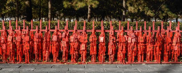 Κινέζικες κόκκινες ευχετήριες κάρτες κρεμασμένες σε μεγάλους αριθμούς στο φράχτη. - Φωτογραφία, εικόνα