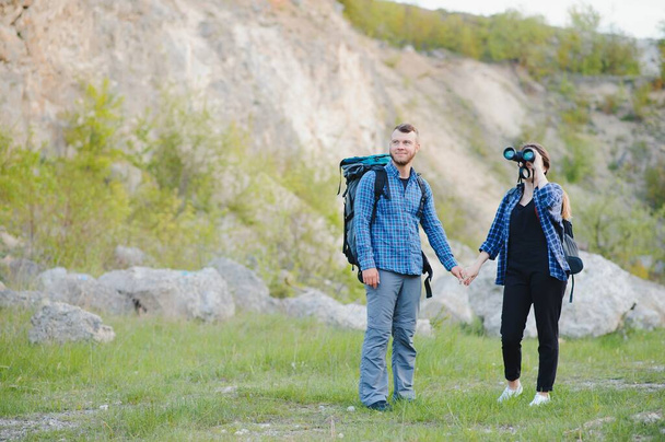 Couple enjoying beautiful views on the mountains, while traveling with backpacks in the mountains during the summer vacations - Photo, image