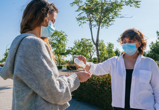 Social distance. Mother pours her daughter disinfectant gel to wash her hands. Mother and daughter in social distancing. Washing their hands. Pandemic. Alcohol disinfectant. Coronavirus. Covid-19. - 写真・画像