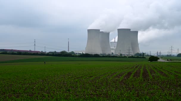 Kerncentrale met vier rookschoorstenen in groene natuurweiden.  - Video