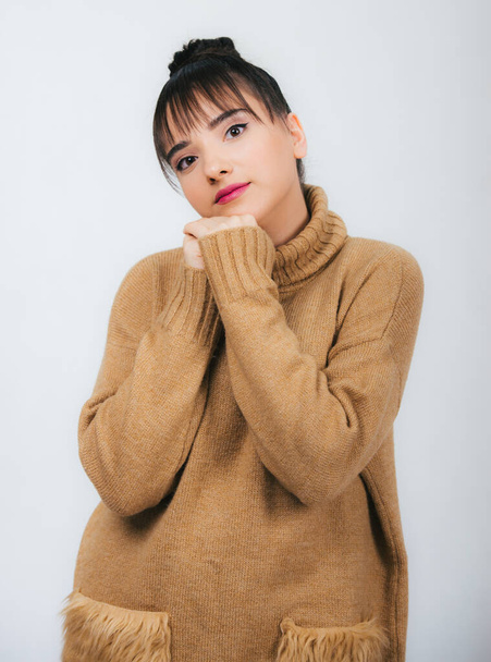 portrait of a beautiful young girl in a brown warm sweater isolated on white background,looking at camera smiling, - Zdjęcie, obraz