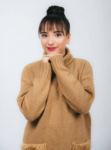 retrato de uma bela menina em um suéter morno marrom isolado no fundo branco, olhando para a câmera sorrindo
, - Foto, Imagem