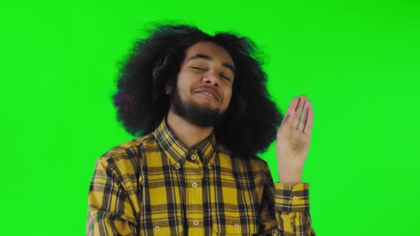 A fiatal afro-amerikai férfi csendet vagy bla bla gesztust mutat zöld vásznon vagy krómkulcsos háttérrel. Az érzelmek fogalma - Felvétel, videó