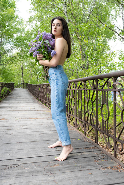 Young girl with a bouquet of lilacs on a foot bridge - Foto, afbeelding