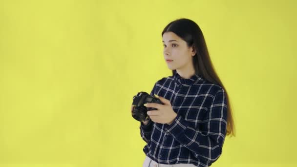 Νεαρό κορίτσι παίρνει φωτογραφία στο κίτρινο φόντο στο στούντιο - Πλάνα, βίντεο