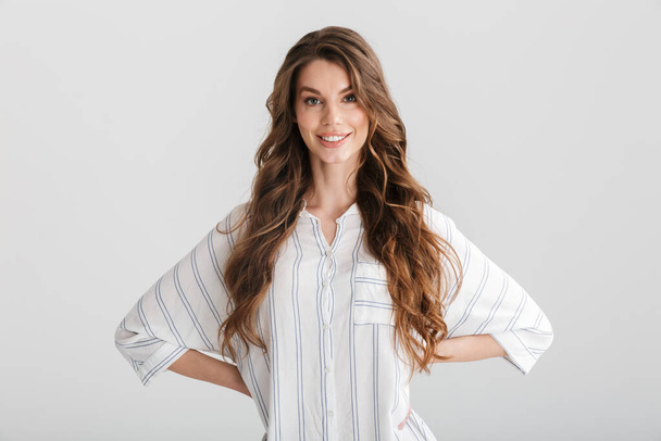 Image of smiling caucasian woman posing with hands on her waist at camera isolated over white background - Foto, afbeelding
