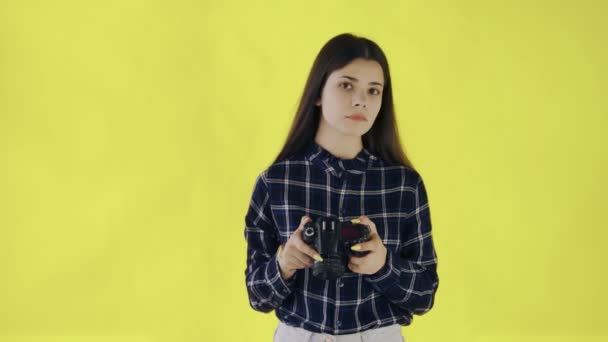Fiatal lány néz kamera és fotózás sárga háttér stúdió - Felvétel, videó