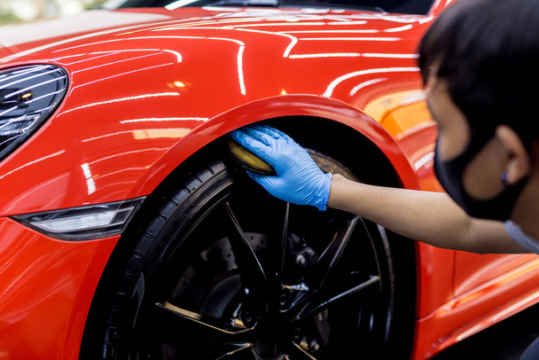 Car service worker polishing car wheels with microfiber cloth. - Photo, image