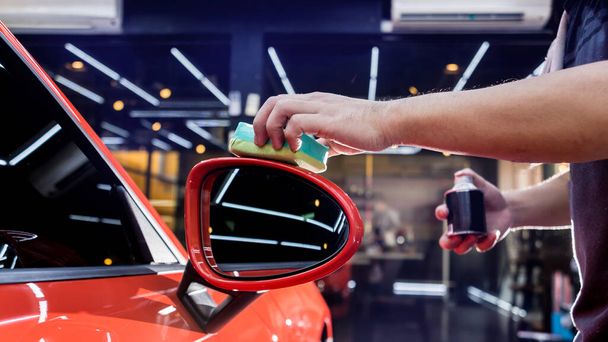 Trabajador de servicio de coches aplicando nano recubrimiento en un detalle del coche - Foto, imagen