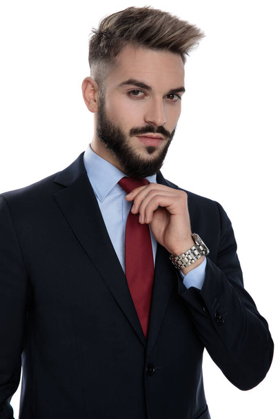 sexy jong zakenman in pak regelen stropdas en staan geïsoleerd op witte achtergrond - Foto, afbeelding