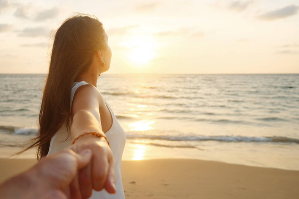 smiling woman runs holding boyfriend hand along ocean coast - Photo, Image