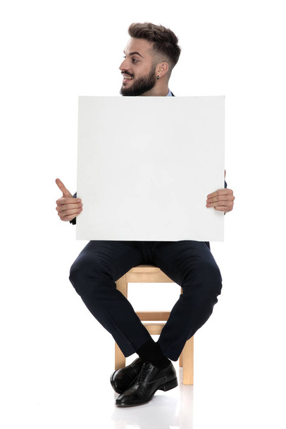 happy young businessman smiling and looking to side, sitting isolated on white background - Φωτογραφία, εικόνα