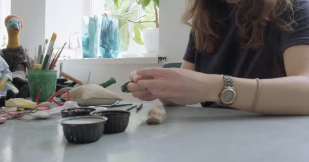 Kobieta robi lalki ceramiczne części z bliska. Kobieta siedzi i tworzy ucho dla lalki w domu przy stole. Części lalek ceramicznych, ręcznie robione i kreatywne umiejętności - Materiał filmowy, wideo