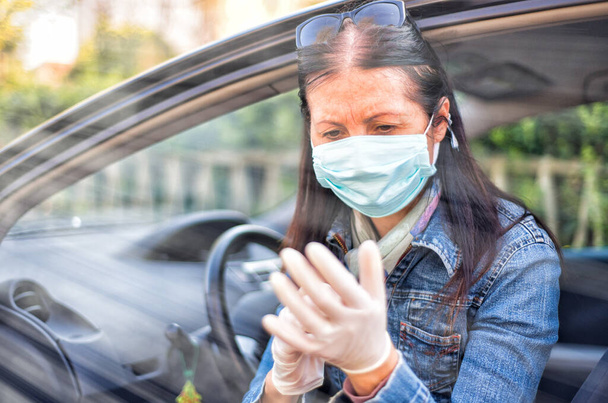 Egy nő, aki kesztyűt fertőtlenít a kocsiban. Coronavirus járványkitörés fogalma. - Fotó, kép