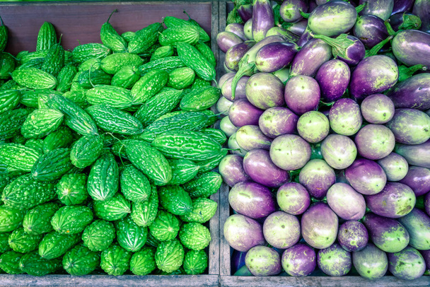 小さなインド、シンガポールの野菜スタンドで鮮やかな緑色の苦いメロンと紫色のアジアのナス - 写真・画像