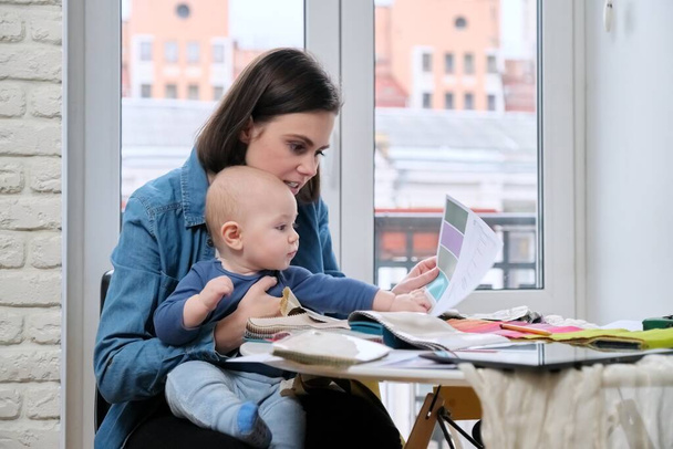Giovane madre lavora con il bambino tra le braccia in ufficio a casa
 - Foto, immagini