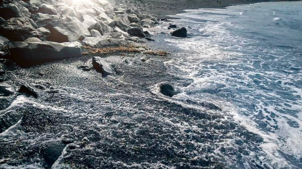 Прекрасный морской пейзаж океанских волн, катящихся и разбивающихся о скалы на вулканическом берегу океана
 - Фото, изображение