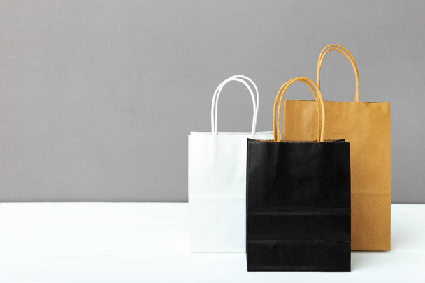 Assortment of different colorscraft paper bags. Shopping Mockup bags paper packages on white table gray background with copy space. Shopping, sale, Food delivery service - Φωτογραφία, εικόνα