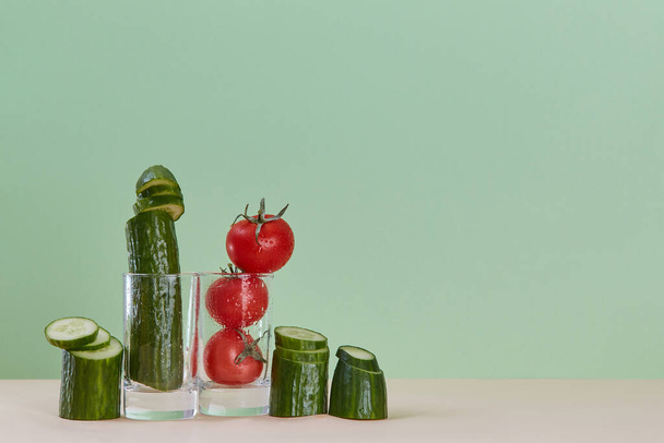 Cucumber and ripe tomato in glass. Fresh juice. Healthy lifestyle concept. Copy space. Isolated on green backdrop - Photo, image