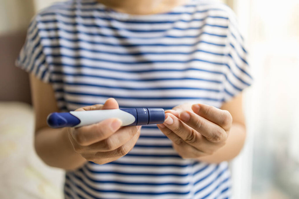lähikuva naisen kädet käyttäen Lancet sormella tarkistaa verensokeri glukoosimittarilla makuuhuoneessa aamulla. Käyttö lääkkeenä, diabetes, glykemia, terveydenhuolto ja ihmisten käsite
. - Valokuva, kuva