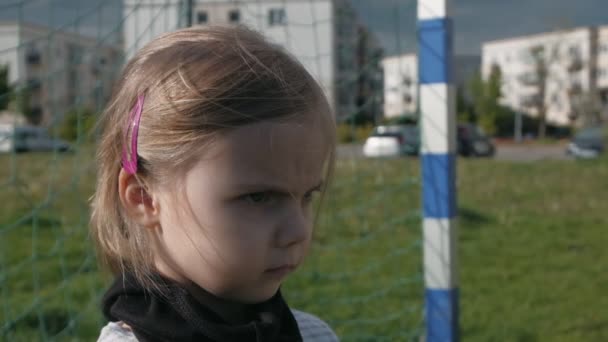 A girl with menacing look in black protective mask stands at football goal. Goalkeeper with stern look. Slow motion - Footage, Video