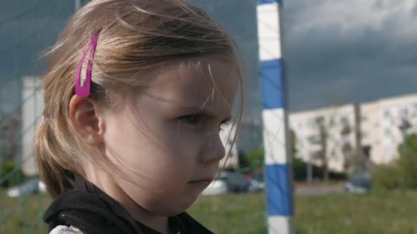 A girl in profile with menacing look stands at football goal and wearing a black mask. Slow motion - Footage, Video