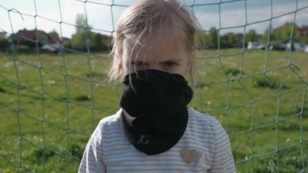 Ένα κορίτσι με απειλητική εμφάνιση με μαύρη προστατευτική μάσκα στέκεται στο τέρμα του ποδοσφαίρου. Τερματοφύλακας με αυστηρή εμφάνιση. Αργή κίνηση - Πλάνα, βίντεο