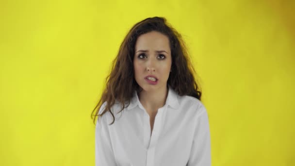 Pensativo jovem bela mulher na camisa de pé em hesitação no fundo amarelo
 - Filmagem, Vídeo