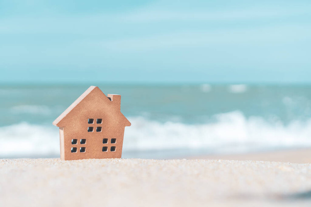 Model of a little house on sand with nature beach background. Dream life concept. - Photo, Image